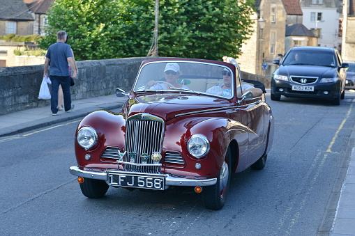 Bradford on Avon, UK - July 22, 2014: A woman drives Sunbeam-Talbot Alpine Sports Roadster on road in the town centre.