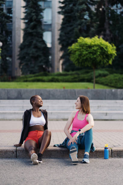 istock Two multiethnic girls relaxing after exercise session, outdoor communicating. 1371526539