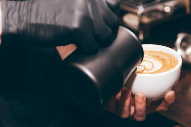Barista holding milk for make coffee latte art in coffee shop stock photo