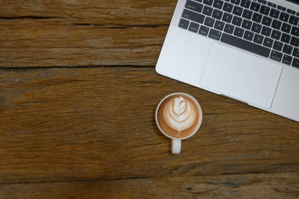 Top view of closed laptop on old wooden table with a cup of coffee. Copy space.