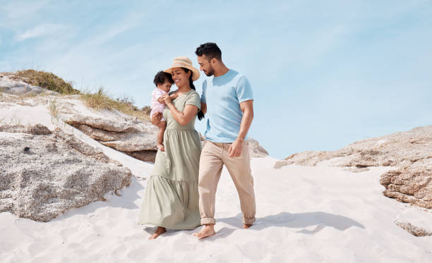 shot of a young couple at the beach with their child - beach two parent family couple family imagens e fotografias de stock