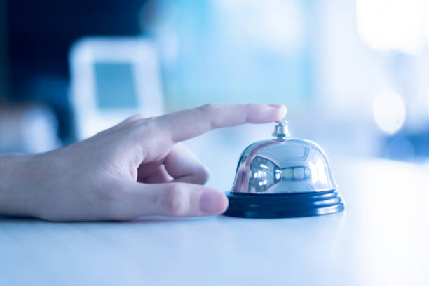 service bell. person using their finger to ring a counter bell.hotel service bell on a table  concept hotel, travel, room service for hotel business.selective focus.wear gloves to prevent covid 19. - sineta imagens e fotografias de stock