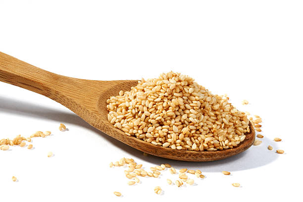 Sesame grains in large wooden spoon Sesame grains in large wooden spoon on white background sesame seed stock pictures, royalty-free photos & images