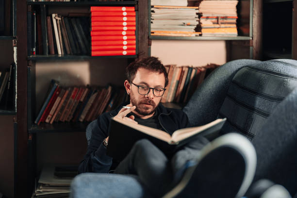 istock Adult student reading a book in the college library while smoking 1371537727