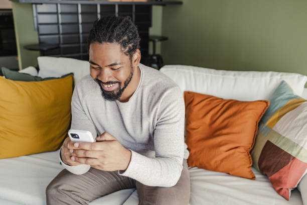 istock Young African-American man using mobile phone at home 1371543544