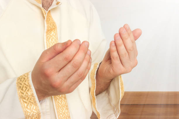 istock Religious caucasian muslim man praying with hands under rays of light. 1371546002
