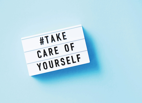 Take care of yourself written white lightbox sitting on blue background. Horizontal composition with copy space.