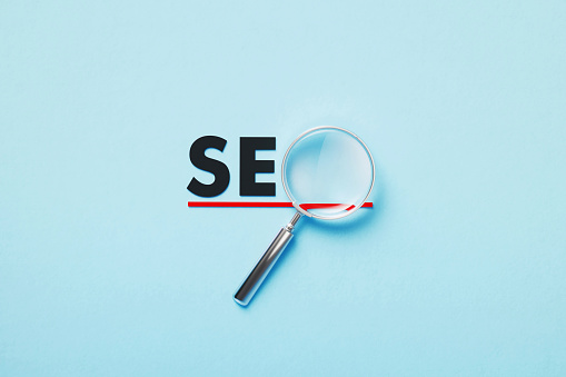 Magnifier forming SEO word on blue background. Horizontal composition with copy space.