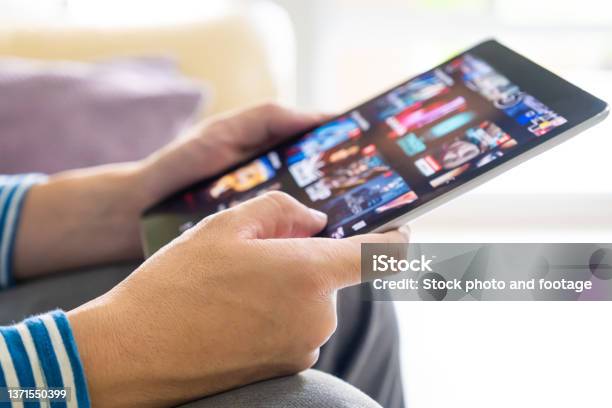 Selective Focus At Men Hand And Digital Tablet Young Adult Asian Man Holding Tablet Device While Choose Online Movie Streaming Application With Mobile Wireless Network At Home Entertainment Concept Stock Photo - Download Image Now