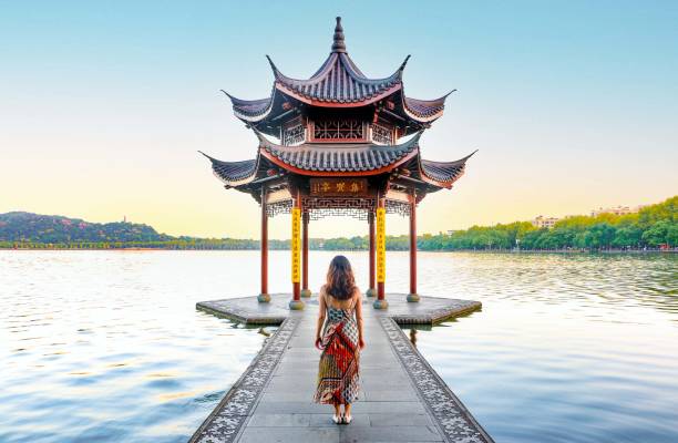 Beautiful Scenery at Hangzhou West Lake, Elegant Woman in dress looks in into the Jixian Pavilion at sunrise Beautiful scenery at Hangzhou West Lake, beautiful and elegant woman in dress looks on into the Jixian Pavilion and the vast lake at sunrise, Chinese characters translate as ‘Jixian Pavilion' pavilion stock pictures, royalty-free photos & images