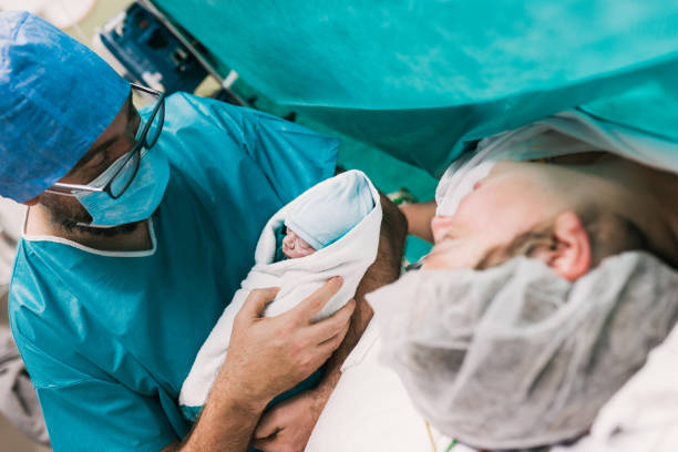medico maschio che mostra il neonato alla madre - cesarean foto e immagini stock