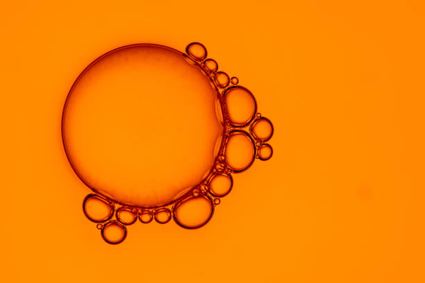 Macrophoto of small bubbles of liquid connecting on one bigger circle in orange color
