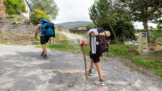 Lugo, Spain - August 12 2021: Camino de Santiago, Way of St James, to the Cathedral of Compostela, Galicia, Spain. Pilgrims with backpackers walk along the pilgrimage
