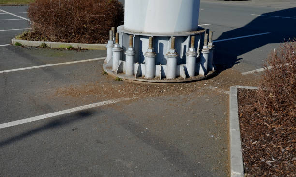 columna de acero gris, viga, atornillada con tornillos grandes masivos a la base de concreto. poste de remonte, alto voltaje, valla publicitaria en el estacionamiento. pilón cilíndrico de acero, tubo - ski lift new design tube fotografías e imágenes de stock