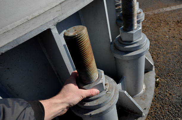 columna de acero gris, viga, atornillada con tornillos grandes masivos a la base de concreto. poste de remonte, alto voltaje, valla publicitaria en el estacionamiento. pilón cilíndrico de acero, tubo - ski lift new design tube fotografías e imágenes de stock