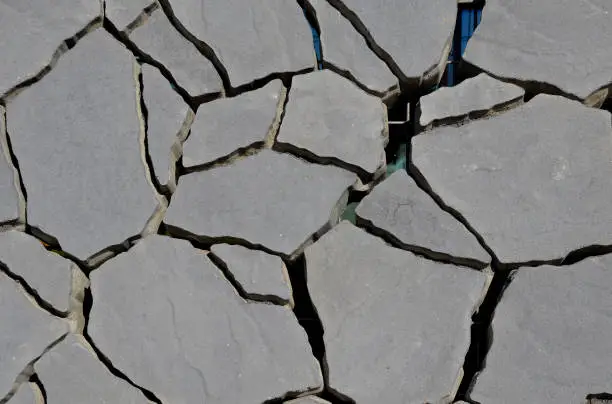 Photo of Irregularly shaped cracked paving block made of concrete. cracked dry soil pattern can be used as drainage paving or in combination with grass,