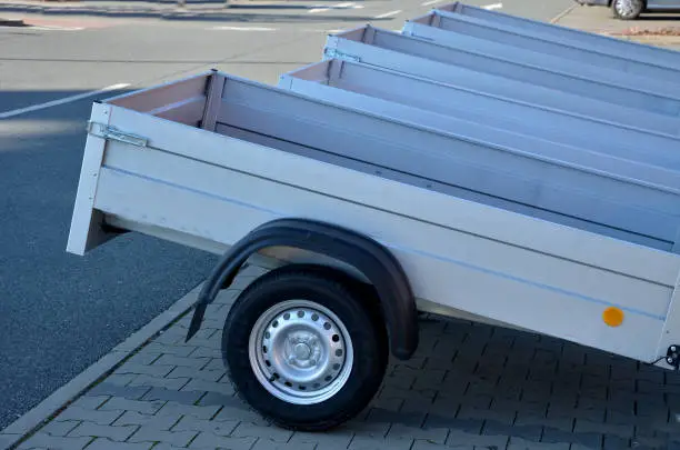 trailer behind a car in the parking lot at the rental shop. just harness to the ball of the towing device. homologation and technical inspections. metal side panels, fender