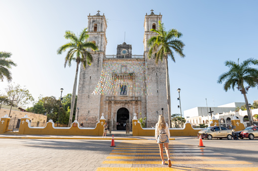 She visits the town square with an old church and palm trees