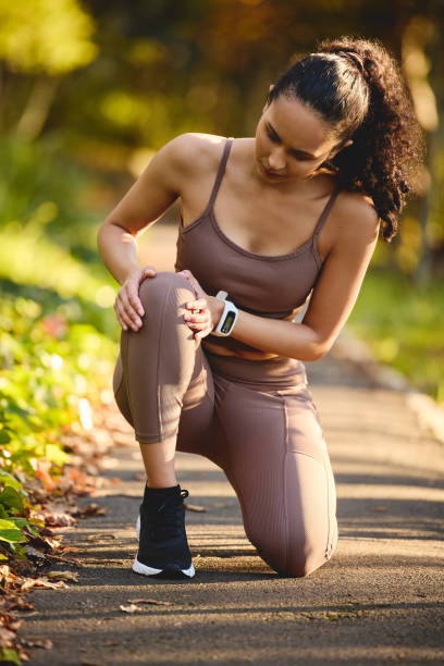 Shot of a sporty young woman experiencing knee pain while exercising outdoors My knee is giving me problems JOINT AND MUSCLE PAIN stock pictures, royalty-free photos & images