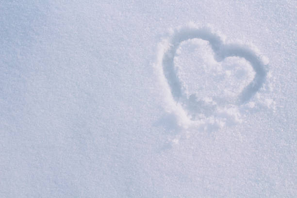 Heart drawn with a finger in the snow. Close-up. Background. Texture.