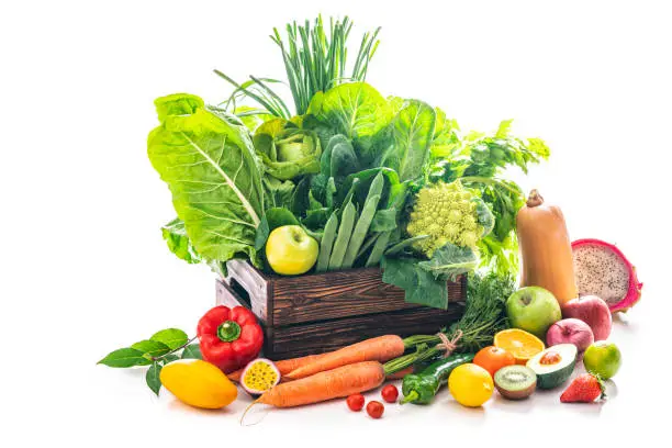 Photo of Assorted fruits and vegetables in a wooden box fresh after harvest isolated on white