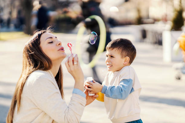 istock A mother blowing bubbles and playing with son in a park. 1371561970