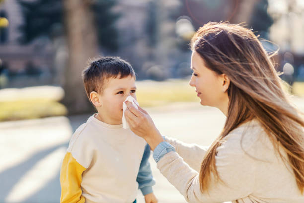 公園でアレルギーのある息子に鼻を吹く母親。 - influenza a virus ストックフォトと画像