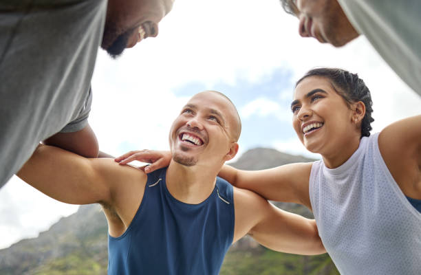 photo d’un groupe de jeunes sportifs debout ensemble dans un groupe tout en faisant de l’exercice à l’extérieur - exercising motivation looking up african descent photos et images de collection