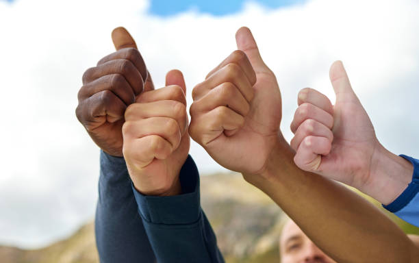 closeup shot of a group of unrecognisable people showing thumbs up while exercising outdoors - exercising motivation looking up african descent imagens e fotografias de stock