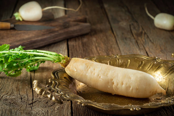 Daikon Turnip white crucifer root vegetable on rustic wood board, asian food in brass tray