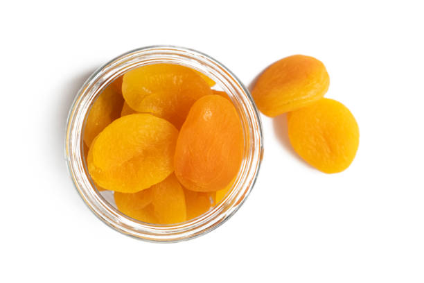 draufsicht auf große getrocknete aprikosen in einer glastasse oder einem glas auf einem weißen tisch. - dried apricot stock-fotos und bilder