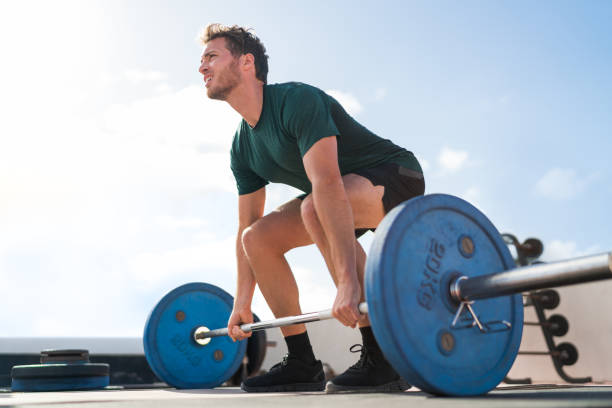 Weightlifting fitness man bodybuilding or powerlifting at outdoor gym. Bodybuilder doing barbell weight workout deadlift with heavy bar. stock photo