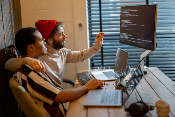 istock Gay couple working on computers at home office 1371570416
