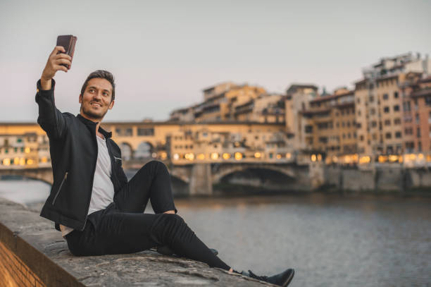 istock Young man taking selfie with smartphone in Florence, Italy 1371574372