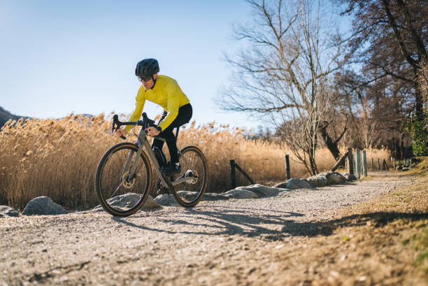ciclista su strada attraversa il soleggiato parco cittadino - racing bicycle bicycle cycling yellow foto e immagini stock