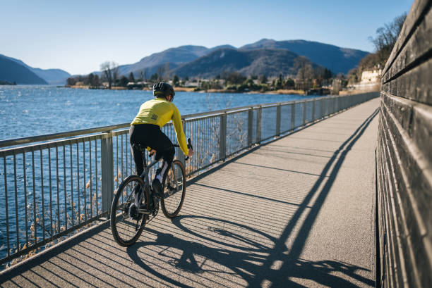 ciclista su strada attraversa il soleggiato lago di lugano - racing bicycle bicycle cycling yellow foto e immagini stock