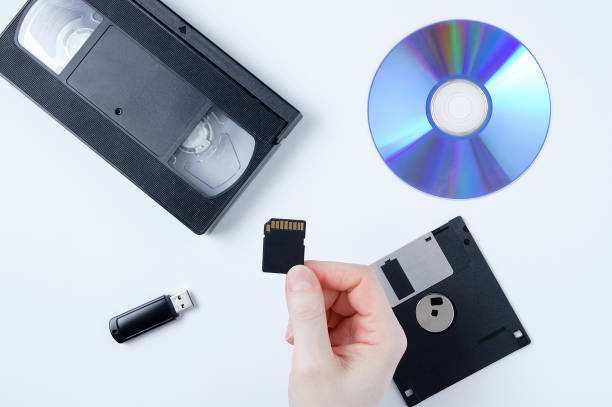 istock Holds a memory card in his hand. Video cassette, flash drive, CD, floppy disk on white background. 1371579753