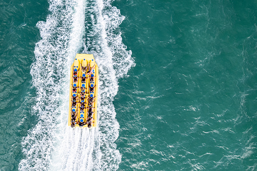 Tourists having fun on a banana boat in an emerald green sea