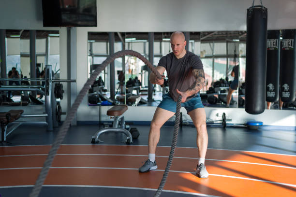 istock Handsome man exercising using battle ropes at a gym, stock photo 1371587399