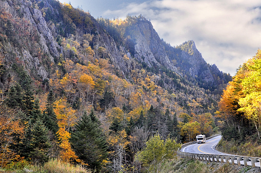 Recreational vehicle (RV) driving through scenic steep-walled gorge in remote and rugged Dixville Notch State Park - the northernmost mountain pass in New Hampshire.