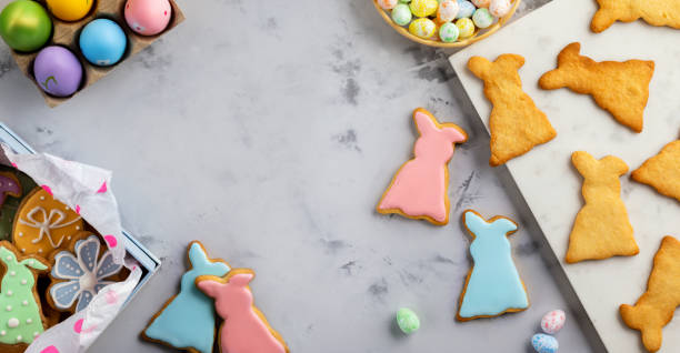 istock Easter greeting card with colorful rabbits, gingerbread cookies and Easter eggs on white table. 1371596421