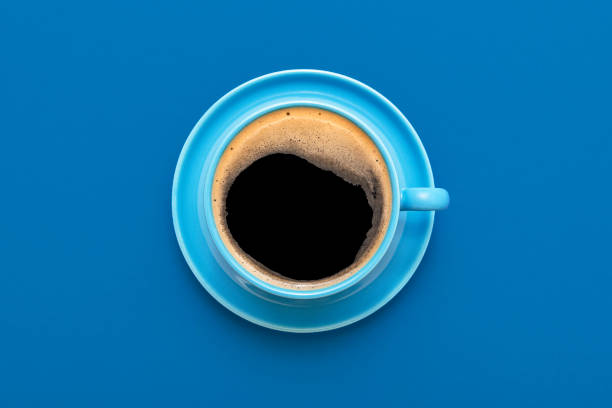 Above view with a single cup of coffee on a blue table. Hot coffee in a blue cup isolated on a colorful background.