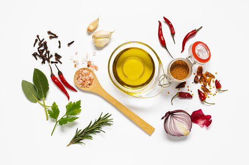 variety of herbs and spices, a bowl with olive oil are arranged on white background. view from above