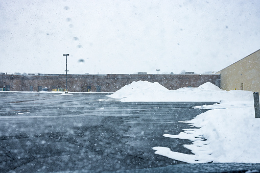 Commercial retail building back parking lot during a February extreme weather winter snow blizzard storm near Rochester, in western New York State.