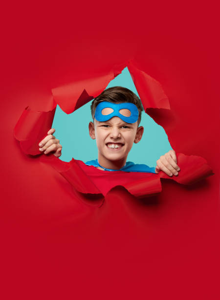 紙の穴�を見てスーパーヒーローの衣装で面白い少年 - 登場 ストックフォトと画像