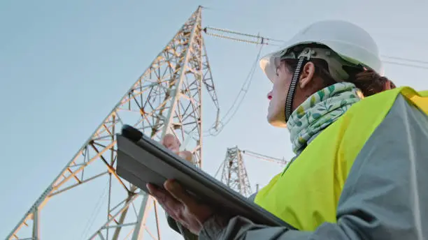 Female electrical engineer working on Electrical Pylons Translation, checking the condition of the Electrical Power Pole components.