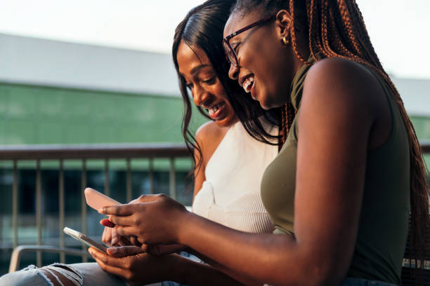 istock two young women laughing while consulting phones 1371621420