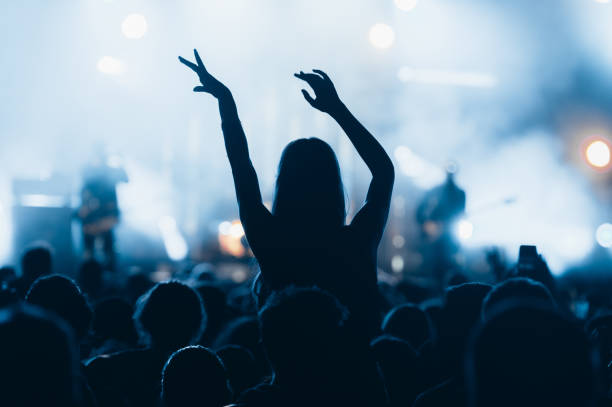 silueta de una mujer con las manos levantadas en un concierto - concierto fotografías e imágenes de stock