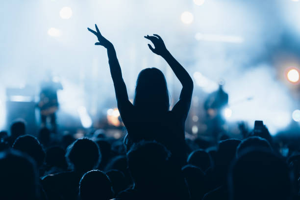 Silhouette of a woman with raised hands on a concert Woman with hands up dancing and having fun during concert show on summer music festival. Youth and celebration concept. concert stock pictures, royalty-free photos & images