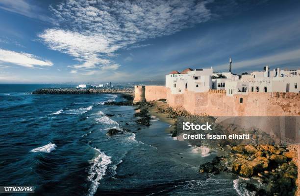 White Painted Historical Buildings And City Wall Of Asilah Against Blue Sky At Coast Morocco North Africa Stock Photo - Download Image Now